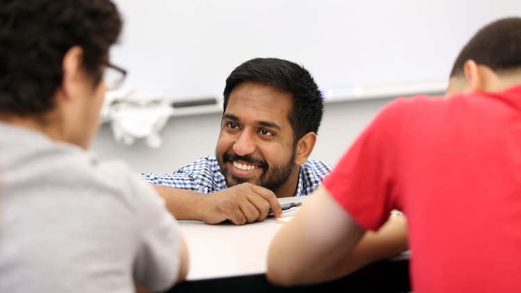 A teacher smiles as he works with his students